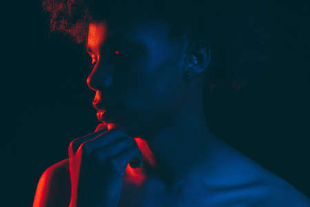 Black man silhouette. Neon light portrait. Thoughtful african male in blue red glow isolated on dark. Fashion model. Masculine power. Aesthetic cosmetologyの写真素材