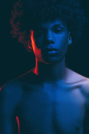 Black man silhouette. Neon light. African guy with shirtless torso in blue red glow isolated on dark. Masculine power. Fashion portrait. Ethnic hairstyle. Freedom mind. Human toleranceの写真素材
