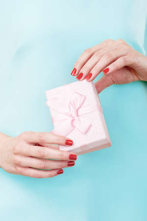 Gift box. Holiday surprise. Female hands holding wrapped present with pink ribbon bow isolated on...