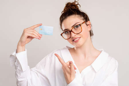 Online transaction. Cash back. Cheerful business woman in white shirt glasses showing credit card...