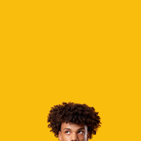 Pensive black teenager. Make decision. Confused young african guy isolated on orange copy space. Human fears. Think idea. Advertising backgroundの写真素材