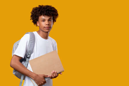 Smart black teenager. Student lifestyle. Smiling african young male with notebook backpack. Looking...