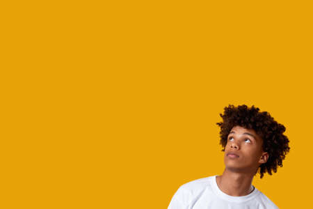 Blaming message. Social pressure. Surprised black teenager boy looking up isolated on orange copy space. Human tolerance. Advertising backgroundの写真素材