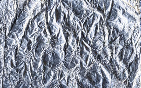 Foil abstract background. Rippled metallic surface. Shiny gray wrinkled texture.の写真素材