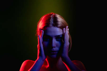 Female silhouette portrait. Feeling exhausted. Frustrated woman in neon light glow holding head...