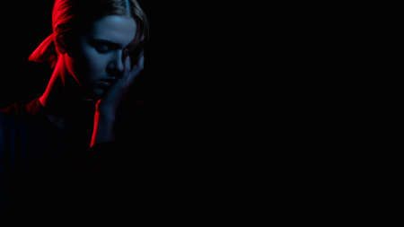 Female silhouette portrait. Psychology support. Exhausted woman crying in neon light glow isolated on black cope space. Domestic violence. Abuse relationship. Stuck problem. Advertising backgroundの写真素材