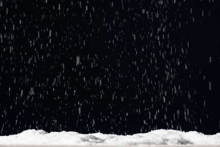 Winter background. Christmas night. Blur white snow flakes falling on pile isolated on black. Defocused ice particles pattern on dark sky abstract wallpaper.の写真素材