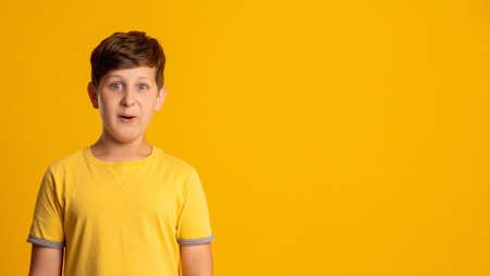 Excited kid. Special offer. Wow reaction. Dream opportunity. Portrait of surprised amazed happy young boy isolated on orange copy space background.の写真素材