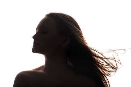 Female silhouette. Soul healing. Profile portrait of inspired woman with bare shoulders closed eyes fly away hair isolated on white empty space background. Aesthetic cosmetology.の写真素材