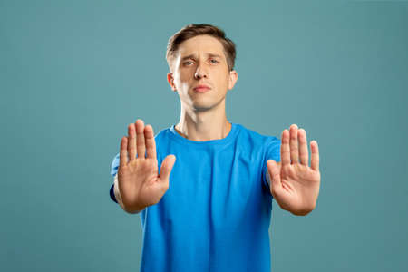 Confident young man holding hands open palms looking at camera isolated on blue.