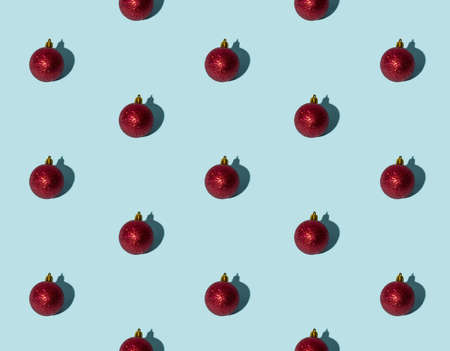 Blue Xmas background. Red bauble seamless pattern. Winter holidays decor. Round shiny glitter ball minimalist composition isolated on light.の写真素材