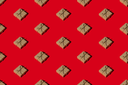 Red Christmas background. Gift seamless pattern. Winter holidays decoration. Long-distance present composition. Rustic beige handmade eco paper boxes with twine isolated on bright.の写真素材