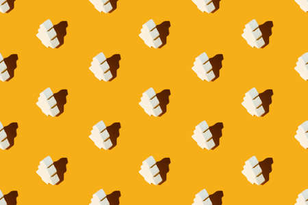 Orange Xmas background. Fir tree seamless pattern. Festive design. New Year party decorative arrangement. White ceramic ornament minimalist composition isolated on bright yellow.の写真素材