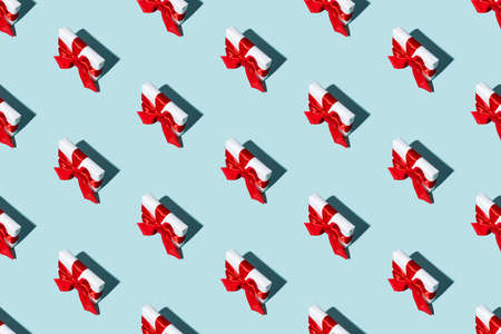 Gift pattern. Blue seamless background. Festive decoration. Long-distance care package. Minimalist composition of white boxes with red ribbon bows isolated on light color.の写真素材