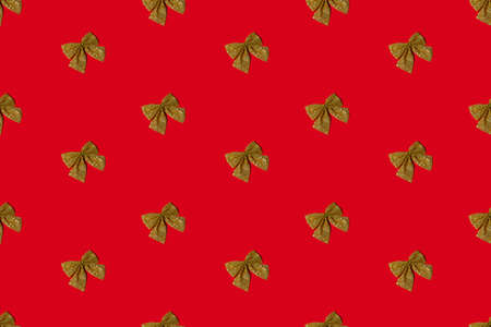 Red Xmas background. Decorative seamless pattern. Gold glitter bow. Festive adornment collection. Symmetrical diagonal composition of sparkling ornament isolated on bright.の写真素材