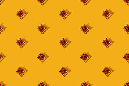 Yellow Christmas background. Drum seamless pattern. Winter holidays celebration decor. Festive adornment. Golden red vintage toy music instrument symmetrical arrangement isolated on bright orange.の写真素材