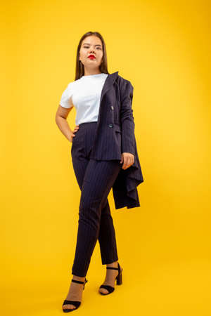 Successful woman. Business fashion. Smart casual look. Female empowerment. Confident ambitious lady in suit standing isolated on orange copy space background.の写真素材