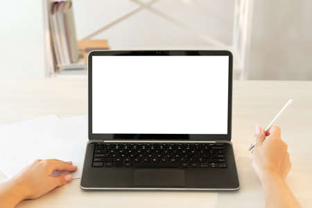 Online education. Videochat meeting. Distance communication. Unrecognizable woman hands making notes laptop blank screen light interior background copy space.の写真素材