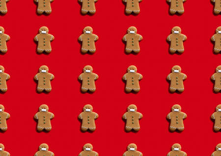 Red pandemic art background. Seamless pattern. Christmas quarantine. Social distancing. Covid-19 winter holidays safety. Beige gingerbread man crowd in protective face masks isolated on bright.の写真素材