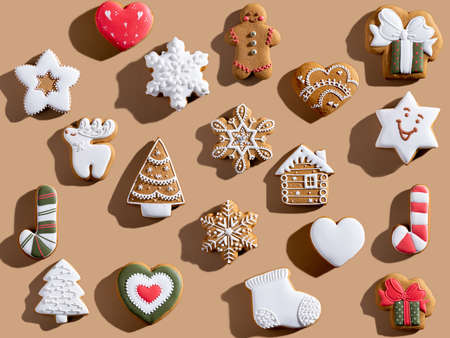 Beige Xmas background. Gingerbread biscuit pattern. Colorful winter holidays bakery food ornament. Homemade cookie collection creative composition isolated on light brown.の写真素材