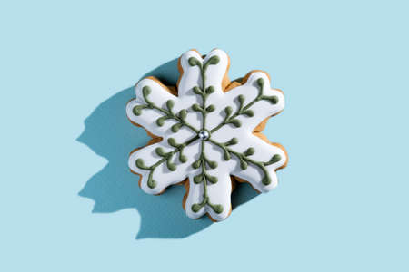 Christmas bakery. Festive decorated cookies. Traditional pastry. Gingerbread star figure biscuit with white icing green ornament isolated on blue pastel.の写真素材
