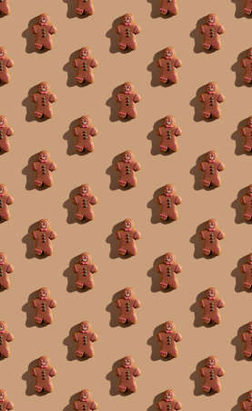 gingerbread pattern. Christmas bakery decor. Festive food background. Biscuit figure man with chocolate icing colorful ornament isolated on beige pastel.の写真素材