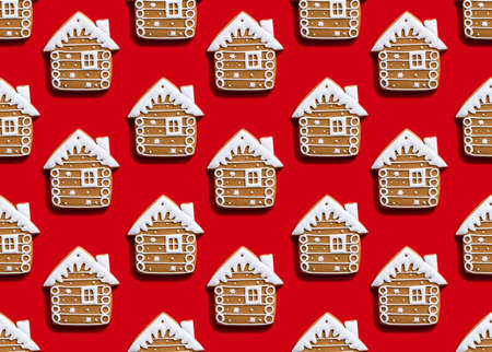 Gingerbread house pattern. Red seamless background. Christmas food ornament. Brown homemade biscuit with white icing minimalist symmetrical arrangement isolated on bright.の写真素材