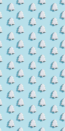Christmas tree pattern. Festive bakery. Traditional cookies. Holiday decor. Sweet white icing figure biscuit isolated on blue pastel.の写真素材