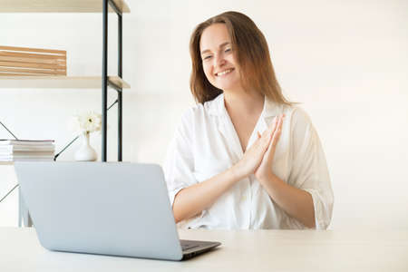 Business webinar. Promotion success. Professional achievement. Corporate teleconference. Cheerful happy female leader receiving congratulations smiling on laptop camera in light home office.の写真素材