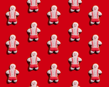 Gay pride. Red seamless background. Lgbt tolerance. Individuality rights. Happy pink gingerbread man biscuit minimalist symmetrical composition isolated on bright.の写真素材