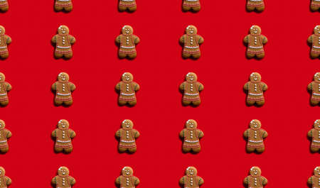 Red food art background. Seamless pattern. Festive dessert ornament. Brown homemade gingerbread woman biscuit with white icing minimalist symmetrical arrangement isolated on bright.の写真素材
