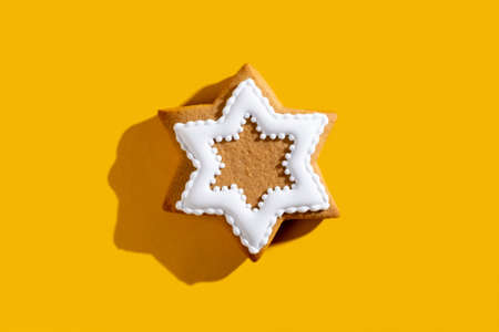 Gingerbread cookie. Sweet decor. Bakery food art. Brown star shape biscuit with white icing adornment for children. Festive ornament isolated on bright orange copy space background.の写真素材