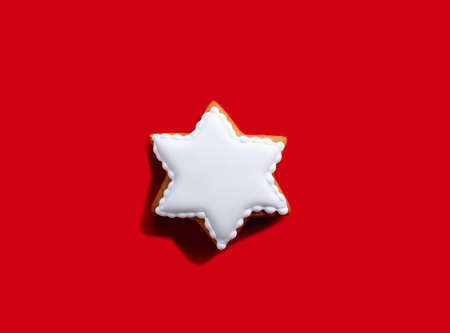 Homemade biscuit. Bakery food art. Festive sweet decoration. White gingerbread star shape cookie ornament isolated on red copy space background.の写真素材