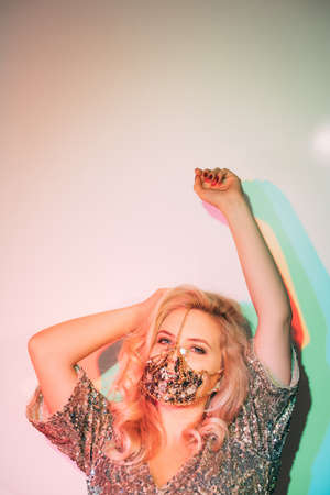 Neon light portrait. Quarantine party. Festive look. Glamour woman in sparkling face mask matching...