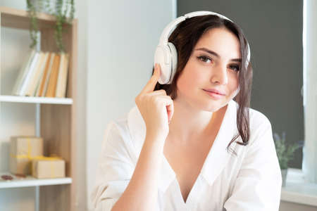 Online education. Webinar training. Videochat conference. Smiling woman in headphones having virtual call looking at camera home workplace interior background.の写真素材