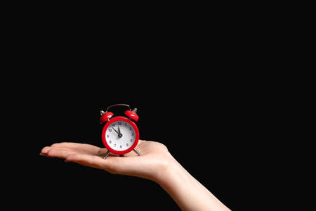 Time management. Deadline reminder. Hurry up. Female hand holding vintage miniature red alarm clock...