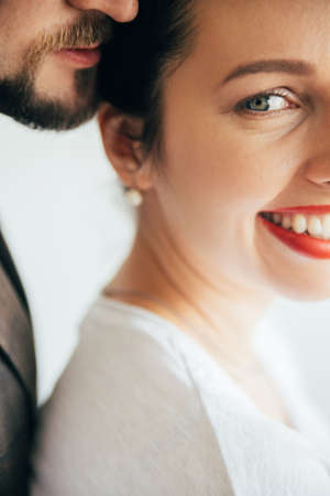 Romantic portrait. Safe moments. Family couple. Happiness affection. Unrecognizable bearded man tenderly embracing beloved smiling woman isolated on white.の写真素材