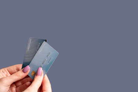Cashless payment. Bank account. Money loan. Ecommerce business. Female client hand holding 2 credit card isolated on purple copy space background.の写真素材