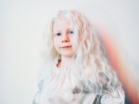 Sweet girl portrait. Child beauty. Fairytale character. Adorable albino little kid with long blonde curly hair blue eyes in white vintage dress on light background.の写真素材