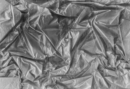 Creased foil background. Crushed texture. Gray aged scratched stained wrinkled plastic polyethylene film with dust particles. Distressed grunge design.の写真素材