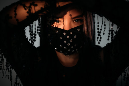 Oriental beauty. Covid-19 protection. New normal style. Stay safe. Asian woman in black paillette dress and decorated crystal beads face mask isolated on gray light shadow.の写真素材