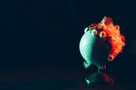 Environmental pollution. Waste conservation problem. Plastic recycling. Ecology damage. Earth globe with transparent wrinkled polyethylene and blossom flowers isolated on black neon light copy space.の写真素材