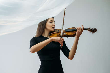 Musician woman. Creativity inspiration. Social distancing. Online concert. Calm lady enjoying playing violin closed eyes with transparent plastic film under head isolated neutral.の写真素材
