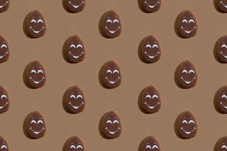 Easter pattern. Seamless banner. Festive pastry art. Homemade cookies. Abstract background. Sweet bakery with chocolate icing and white smiling face decoration isolated on beige.の写真素材