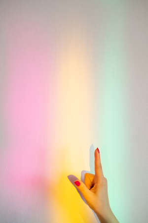 Pointing gesture. Information banner. Notice sign. Text message. Advertising background. Female hand with finger up on blur rainbow glowing neon lights.の写真素材