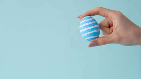 Easter ornament. Holiday decor. Festive food craft. Painted egg with white simple modern stripe...