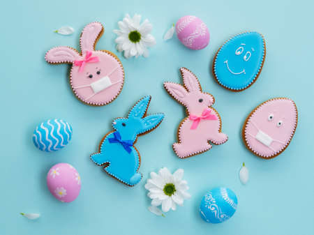 Pink blue gingerbread biscuit bunny egg with face in mask design white flowers isolated on light background.の写真素材