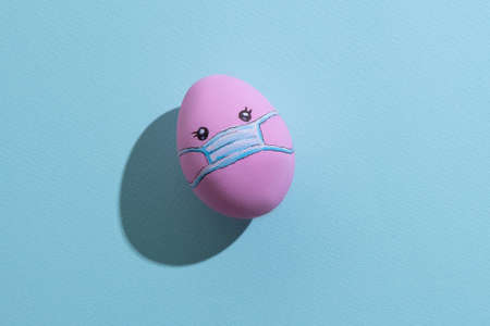 Pink painted figure with medicine mask ornament isolated on blue textured.の写真素材