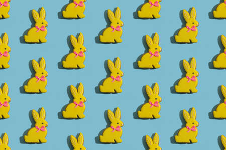 Pretty rabbit gingerbread cookies with yellow icing isolated on blue textured.の写真素材