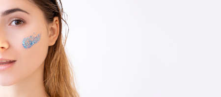 Skin care. Beauty banner. Cosmetic product advertising. Half face portrait of woman perfect smooth face with blue beads gel scrub cleanser stroke isolated on white copy space background.の写真素材